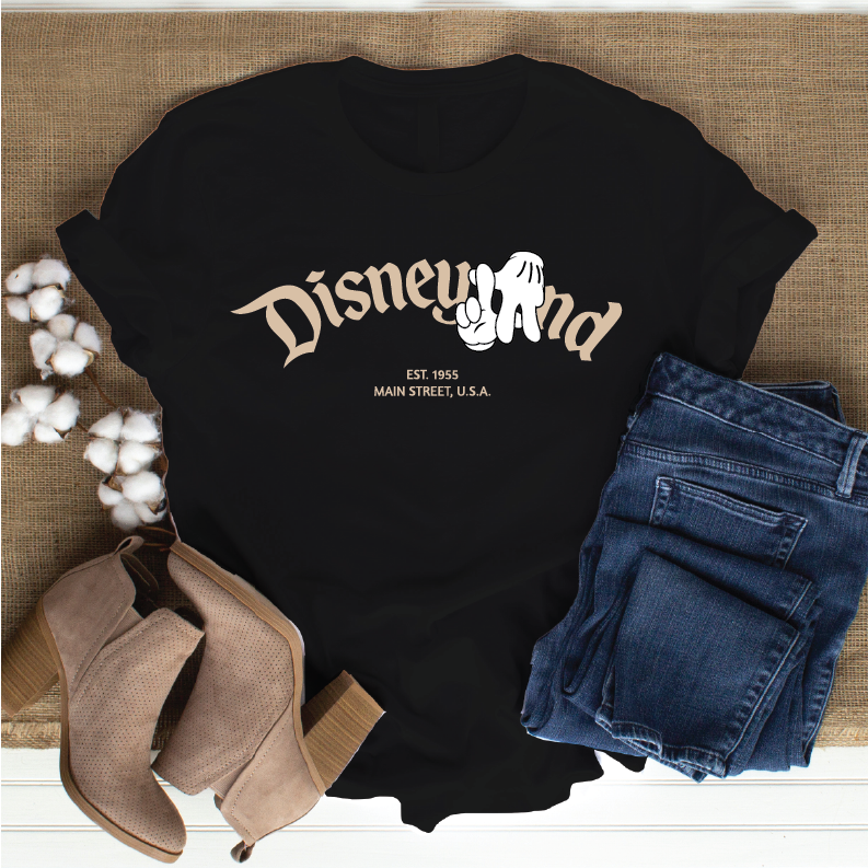 tan ankle boots, and cotton bolls. The shirt has a large beige 'Disneyland' script with a white Mickey Mouse graphic 