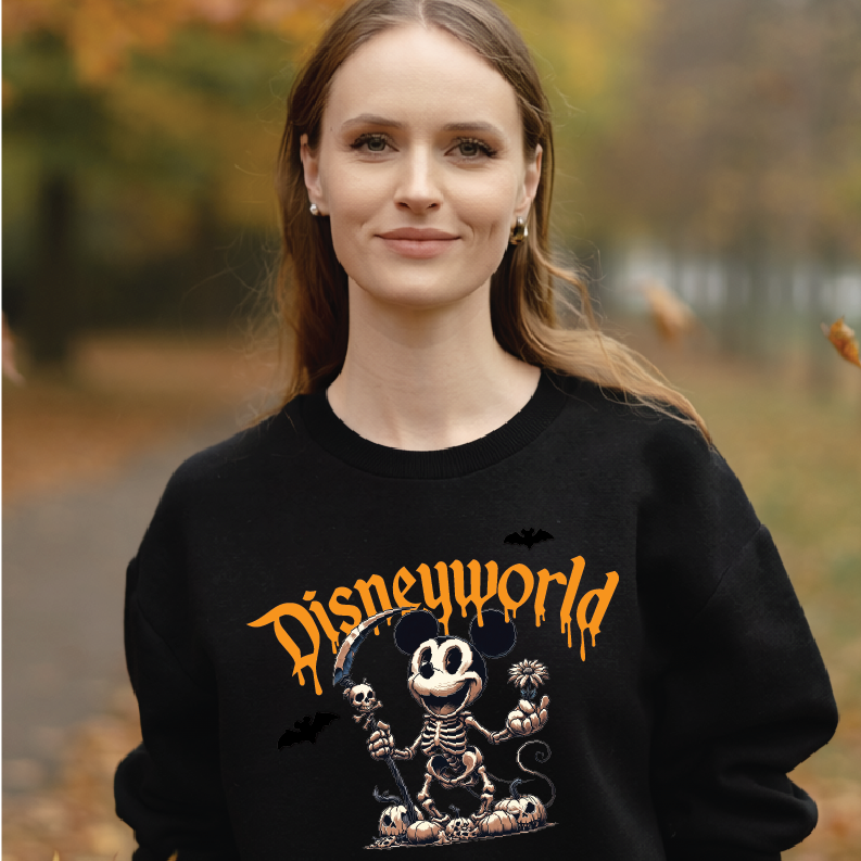 A woman wearing a black Disneyworld Halloween sweatshirt with a skeleton Mickey Mouse graphic and orange 'Disneyworld' text, set against a blurred autumn park background.