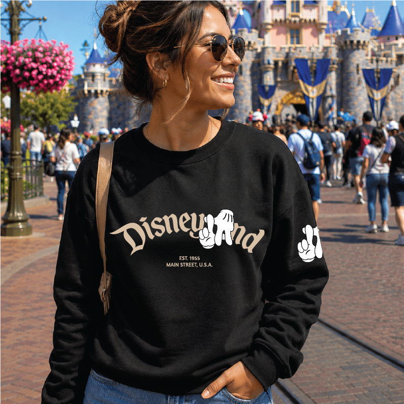 A woman wearing a black Disneyland sweatshirt with a white graphic print, standing in front of the iconic castle at Walt Disney World.