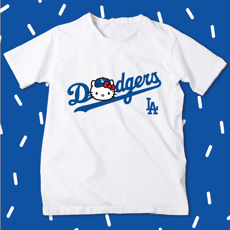 A white short-sleeve t-shirt featuring a blue 'Dodgers' script logo with a Hello Kitty character integrated into the design, and a blue 'LA' logo on the right chest. The shirt is displayed flat against a blue background with white dashed line patterns.