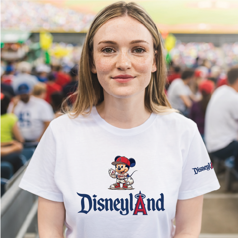 A woman wearing a white Disneyland t-shirt with a Mickey Mouse graphic and the Disneyland logo, standing in a crowded stadium setting.