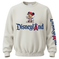 An off-white crewneck sweatshirt featuring a Mickey Mouse baseball graphic above the text 'Disneyland' in blue and red, with 'Disneyland' printed down the right sleeve.