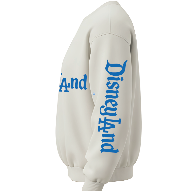 An off-white crewneck sweatshirt shown from a side profile view, featuring 'Disneyland' printed in a blue Gothic font down the right sleeve and across the chest.